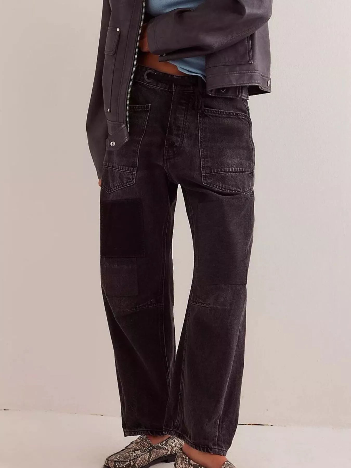 Person wearing black wide-leg jeans with a plain background