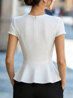 White peplum top with pearl details worn by a person, blurred background