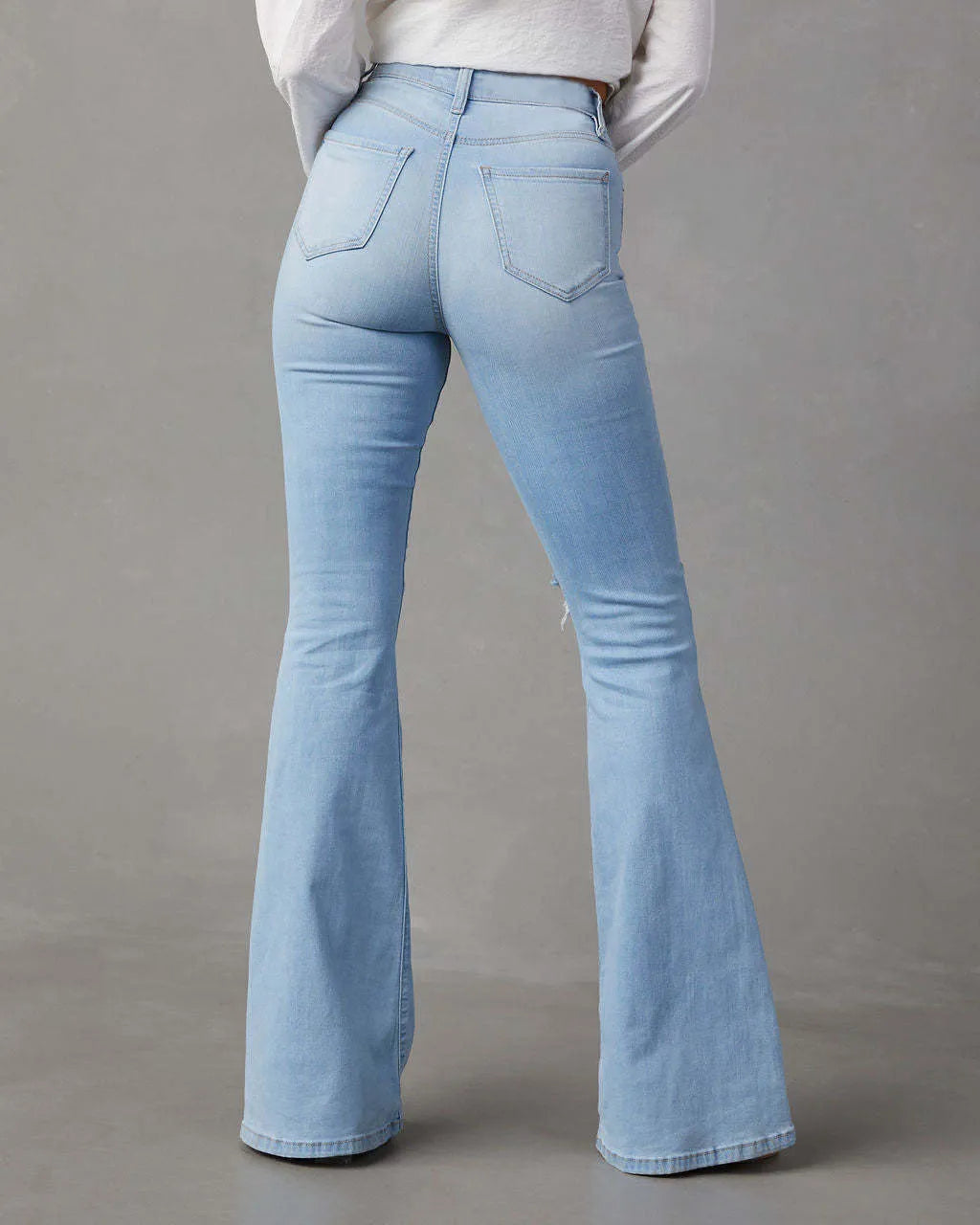 Light blue flared jeans on a gray background