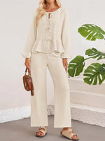 Woman wearing a beige outfit with a plain background and green leaves.