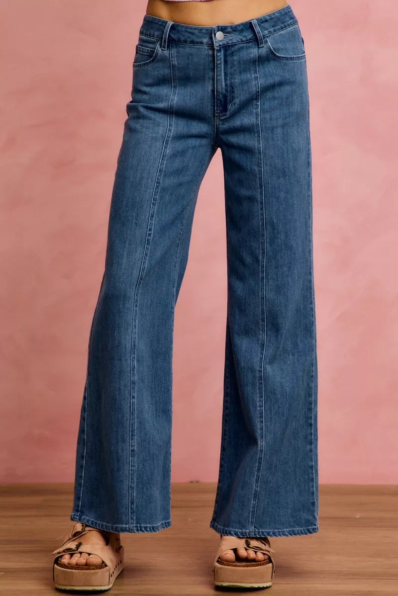 Blue jeans worn by a person on a pink background