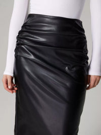 Black leather skirt worn by a person on a plain background