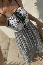 Person wearing a black and white patterned dress on a stone pavement.