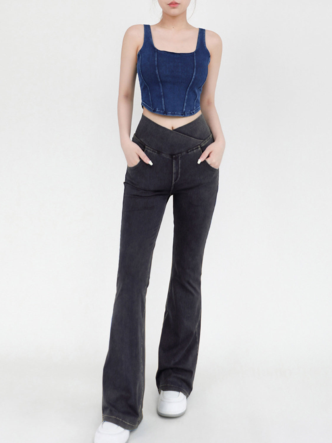 Person wearing a blue denim crop top and black flared jeans on a white background
