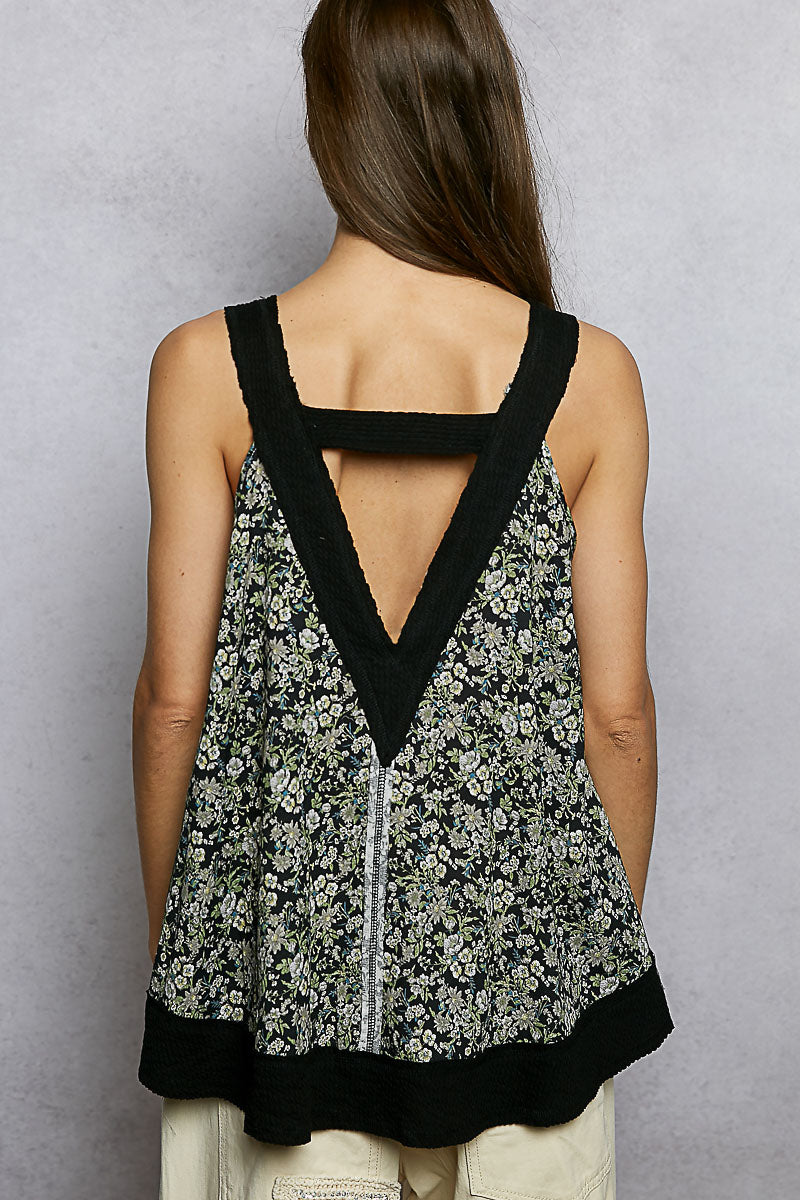 Woman wearing a floral tank top with black trim on a gray background