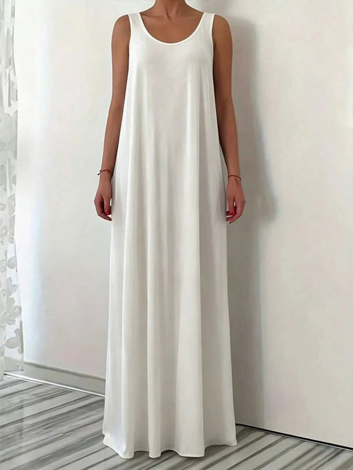 Woman wearing a long white dress against a plain background