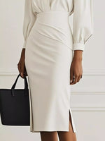 Person wearing a white dress with a black handbag on a plain background