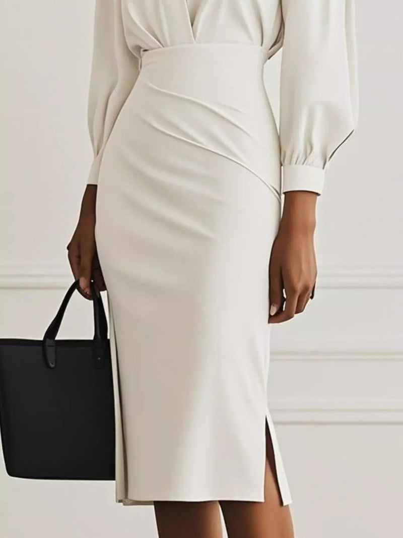 Person wearing a white dress with a black handbag on a plain background