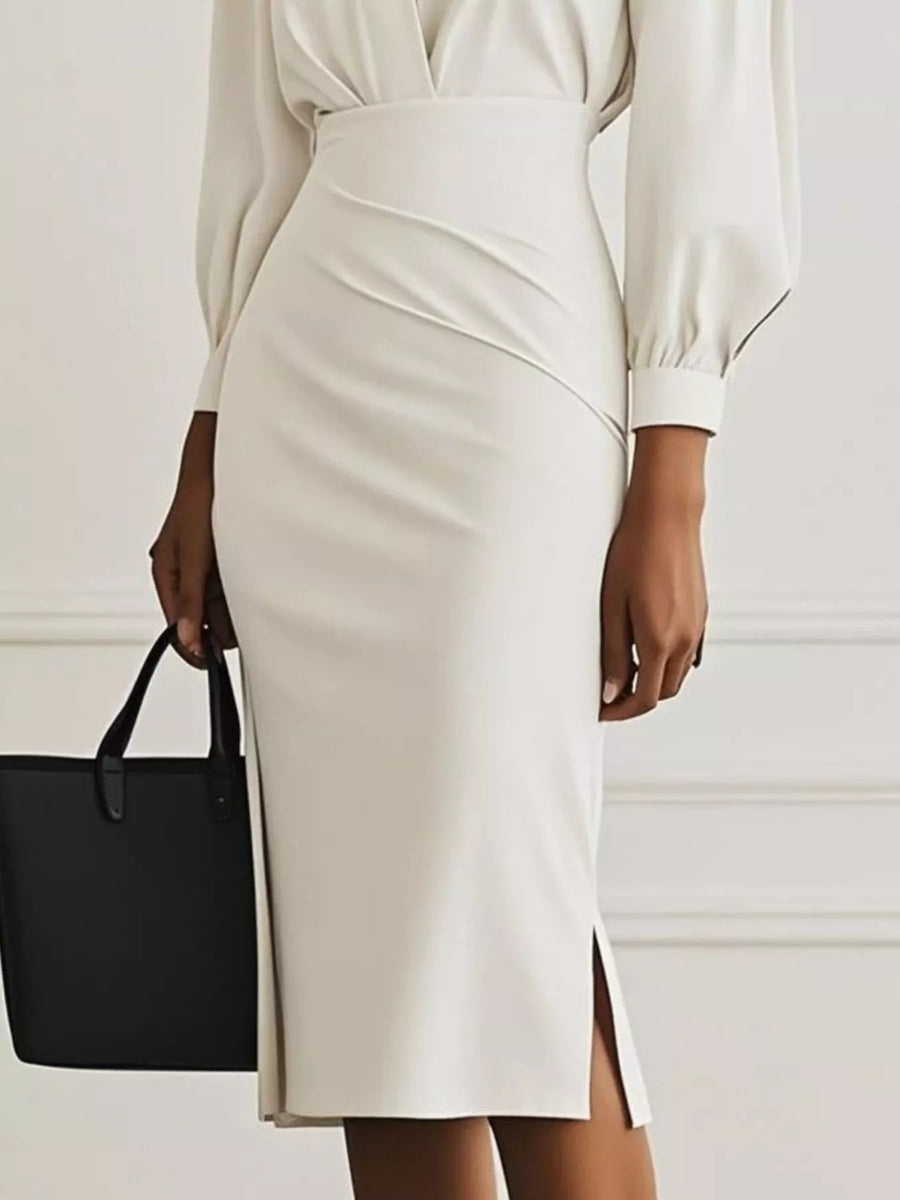 Person wearing a white dress with a black handbag on a plain background