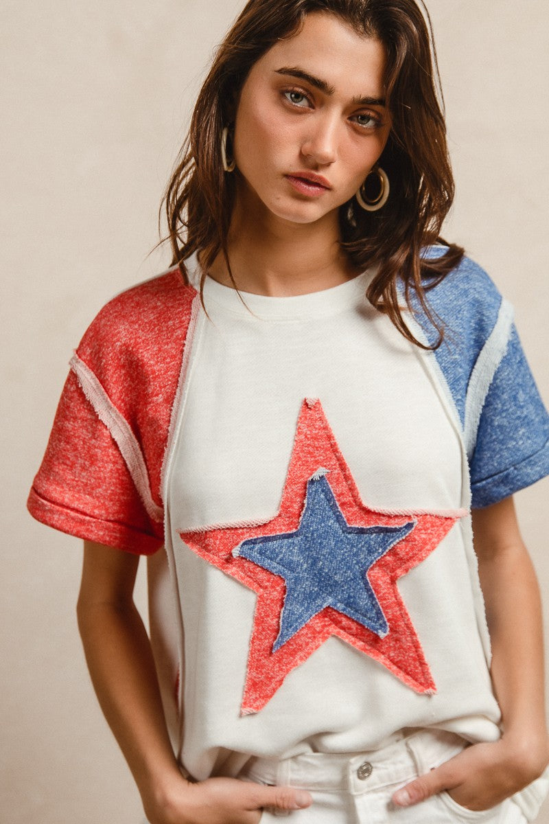 Woman wearing a white t-shirt with a red and blue star design on a beige background