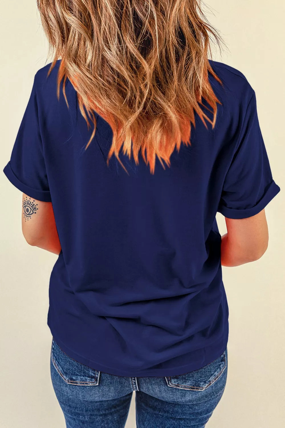 Person wearing a navy blue t-shirt and blue jeans with a neutral background