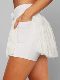 White tiered skirt worn by a person on a gray background