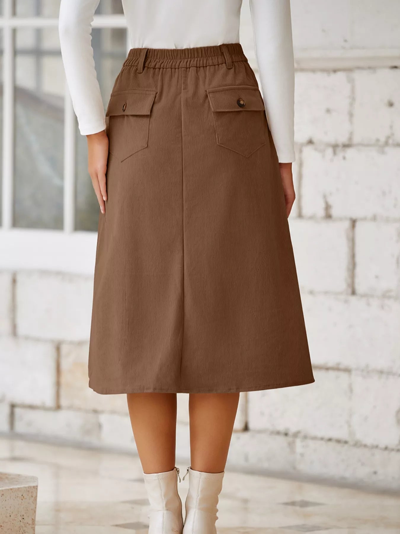 Brown skirt worn by a person against a light stone wall.