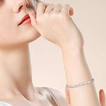 Close-up of a woman's hand wearing a silver bracelet on a beige background