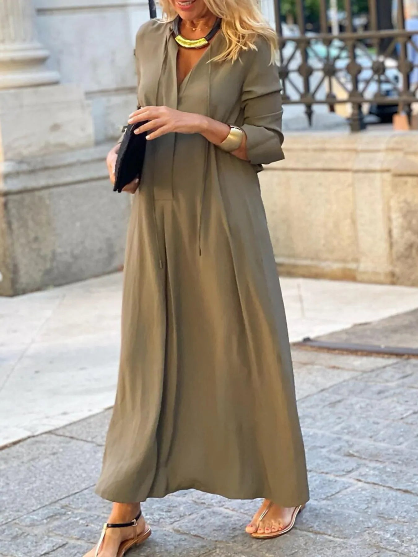 Woman wearing a long olive green dress in an urban setting