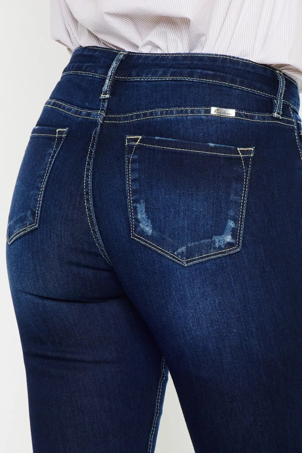 Blue jeans with a white shirt underneath on a light gray background