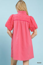 Woman wearing a pink dress with puff sleeves against a light blue background