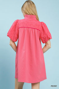 Woman wearing a pink dress with puff sleeves against a light blue background