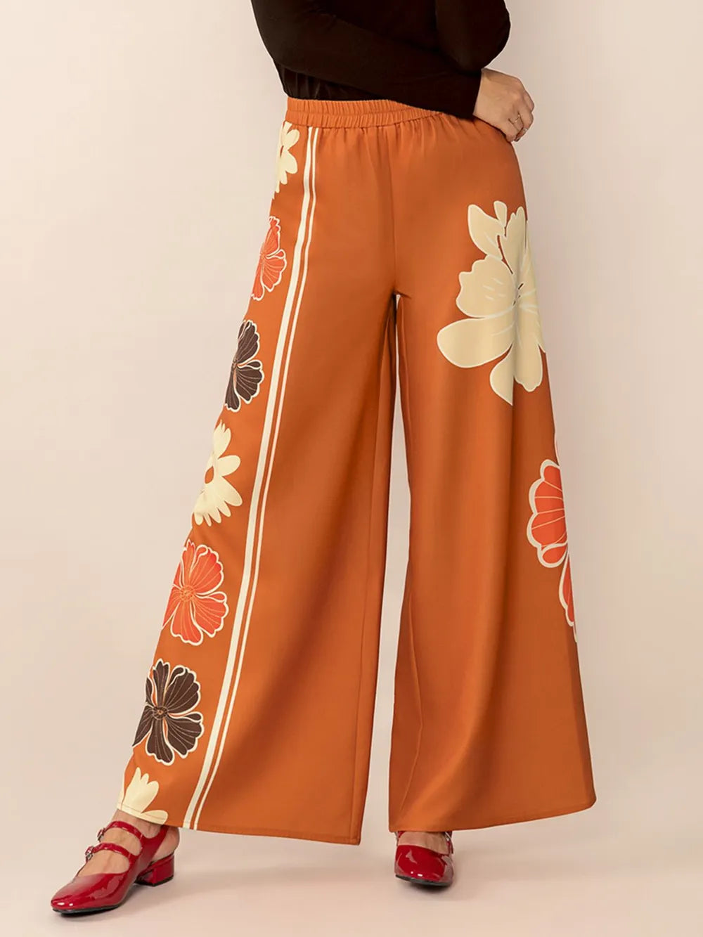 Orange floral pants with white stripes on a beige background