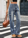 Person wearing blue cargo jeans with a brown leather bag on a street.