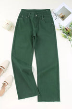 Green pants on a white surface with a cup and plant in the background