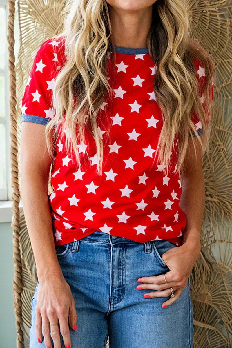 Person wearing a red top with white star pattern and blue jeans against a textured wall.