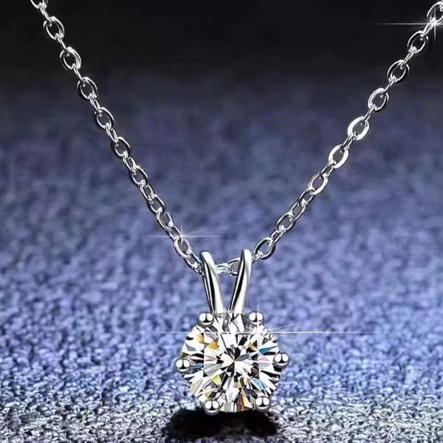 Silver necklace with a diamond pendant on a textured gray background
