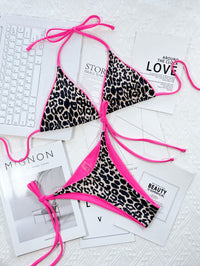 Leopard print bikini with pink straps on a textured surface