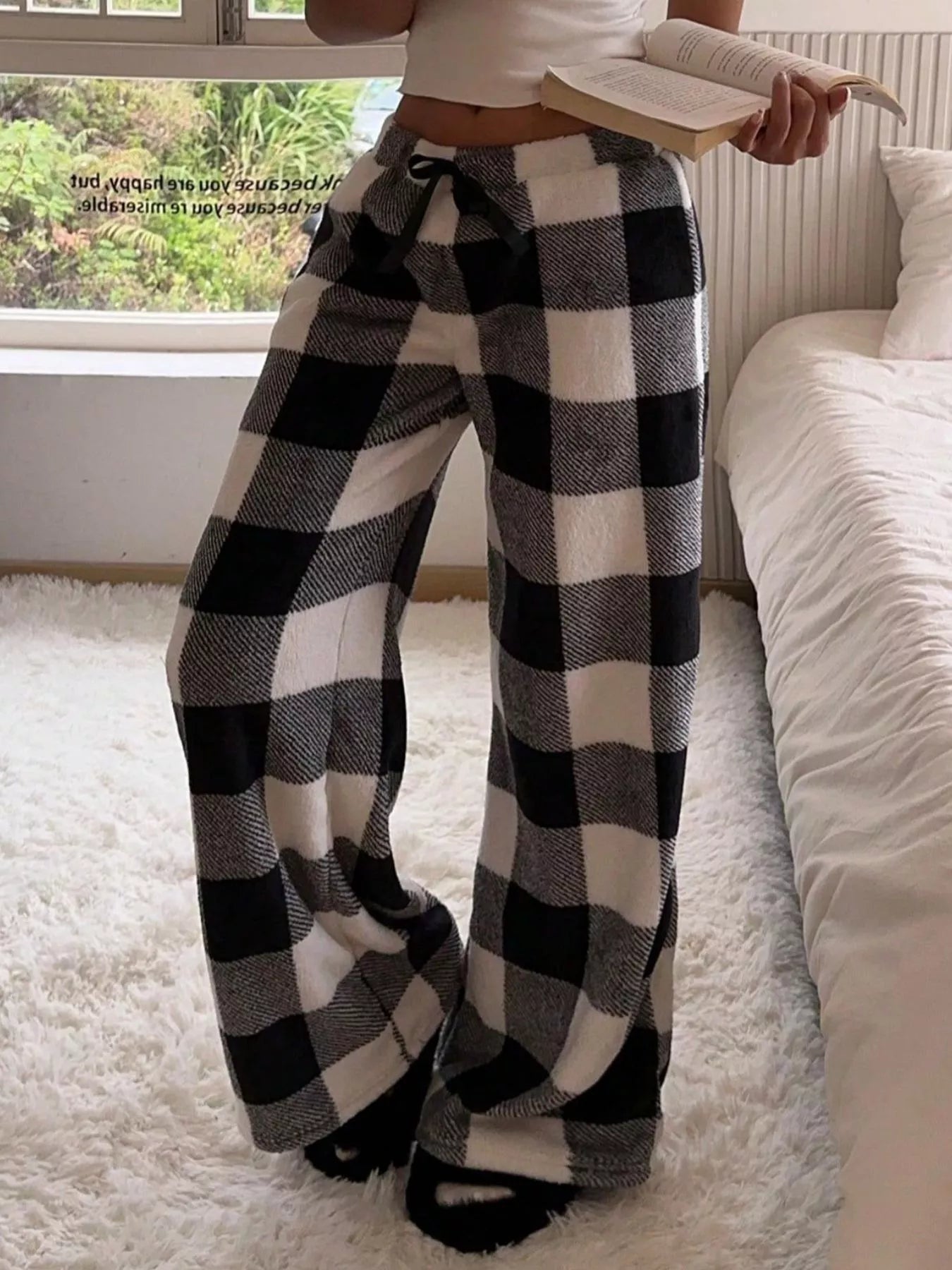Person wearing black and white checkered pants in a cozy room.