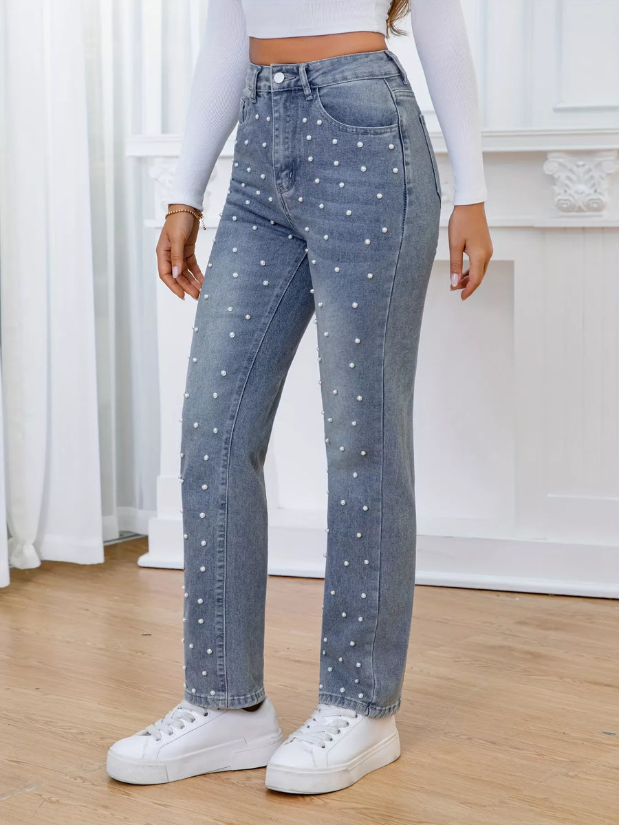 Person wearing blue jeans with white polka dots and white sneakers indoors.