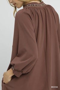 Brown dress with long sleeves and a high neckline on a white background