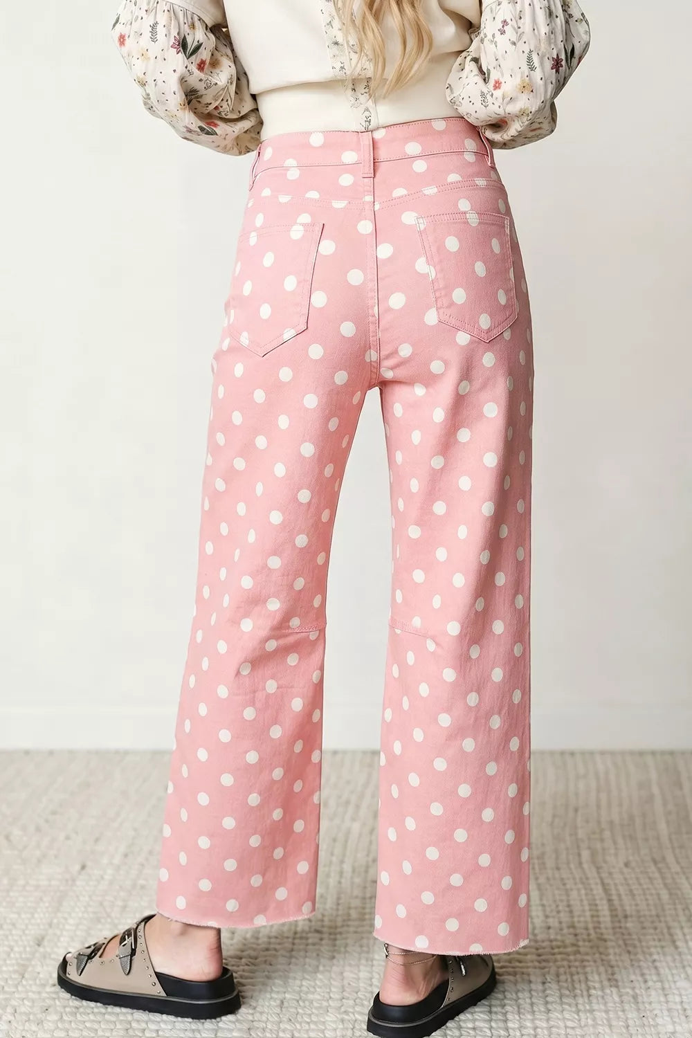 Person wearing pink polka dot pants with a plain background