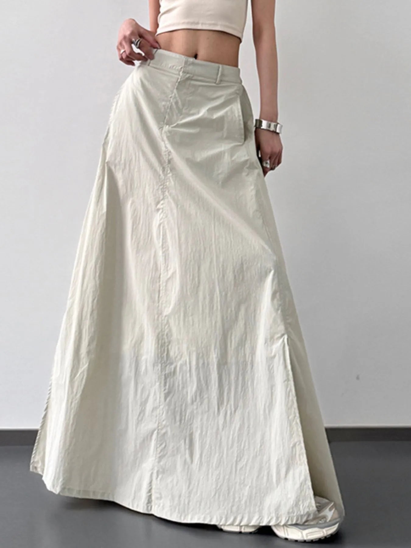Person wearing a long light-colored skirt against a plain background