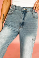 Close-up of light blue jeans with a star patch on a pink background
