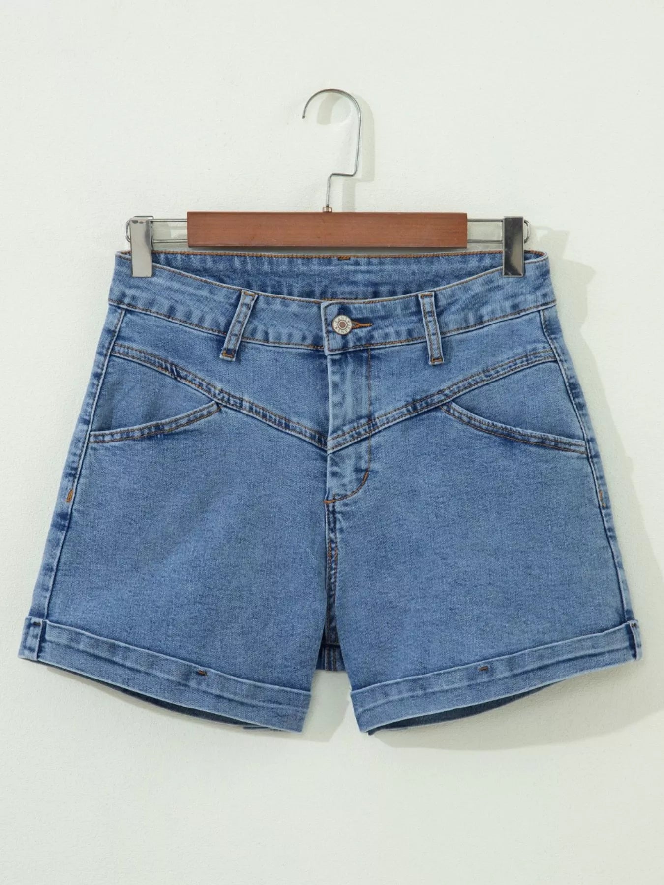 Blue denim shorts on a hanger against a white background