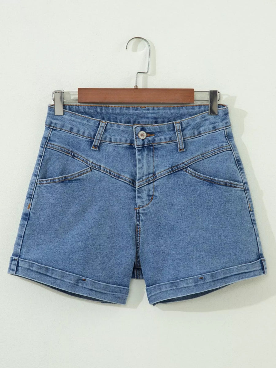Blue denim shorts on a hanger against a white background