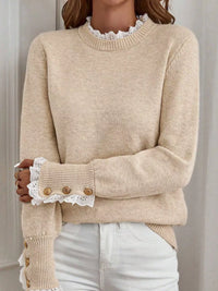 Beige sweater with lace cuffs and buttons on a neutral background