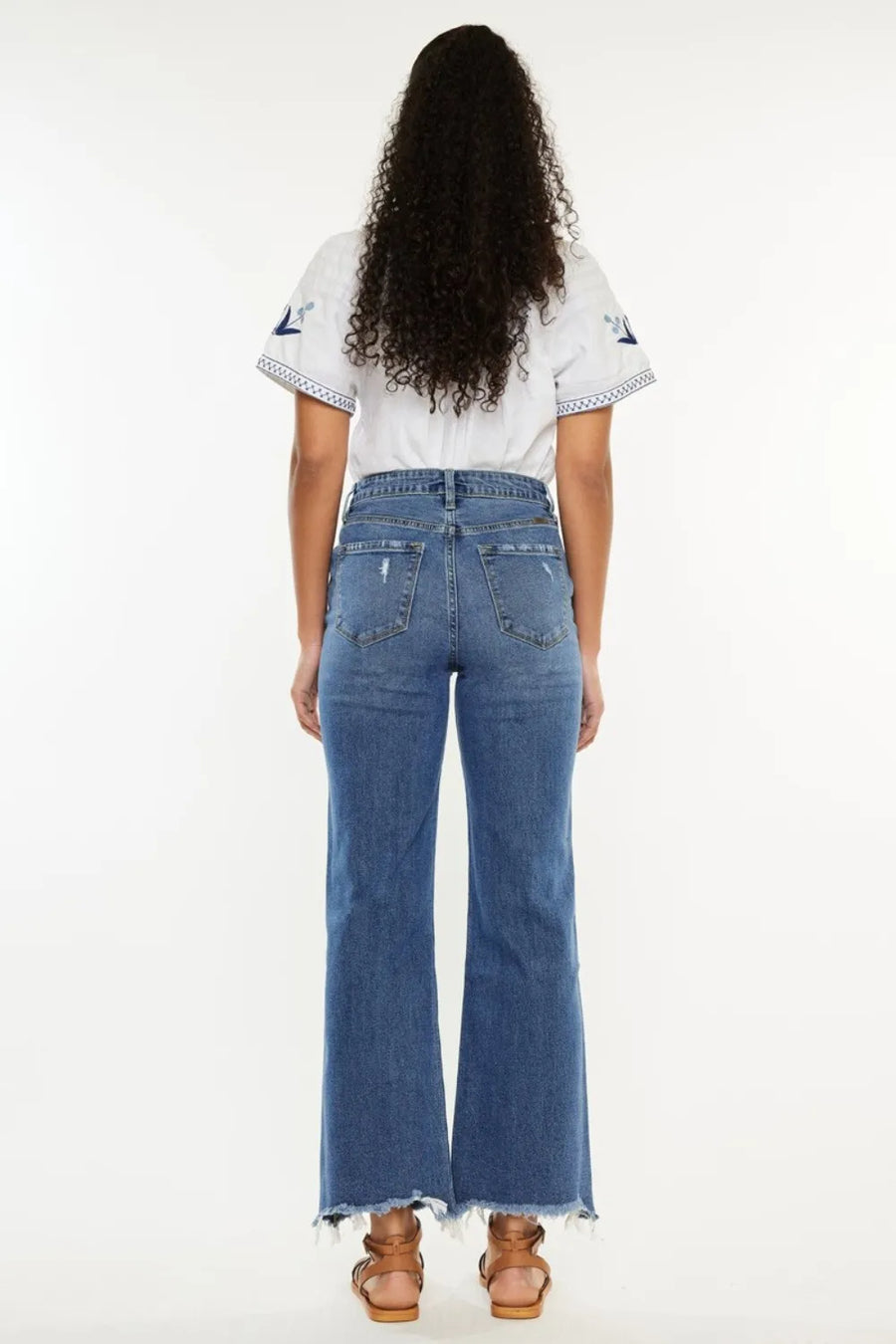 Person wearing a white top and blue jeans on a white background