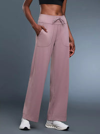 Person wearing mauve wide-leg pants on a gray background