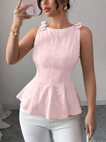 Woman wearing a pink peplum top and white pants, taking a mirror selfie.