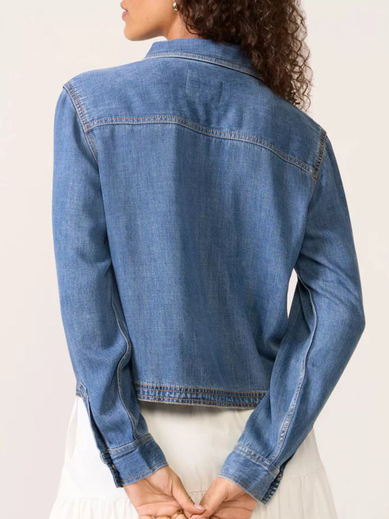 Blue denim jacket worn by a person on a light background