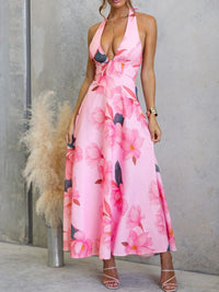 Woman wearing a pink floral dress against a gray wall.