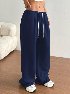 Navy blue wide-leg pants with a white drawstring worn by a person indoors.