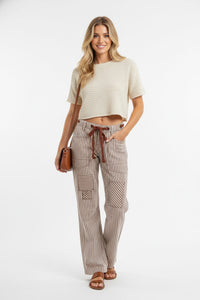 Woman wearing a beige top and striped pants on a white background