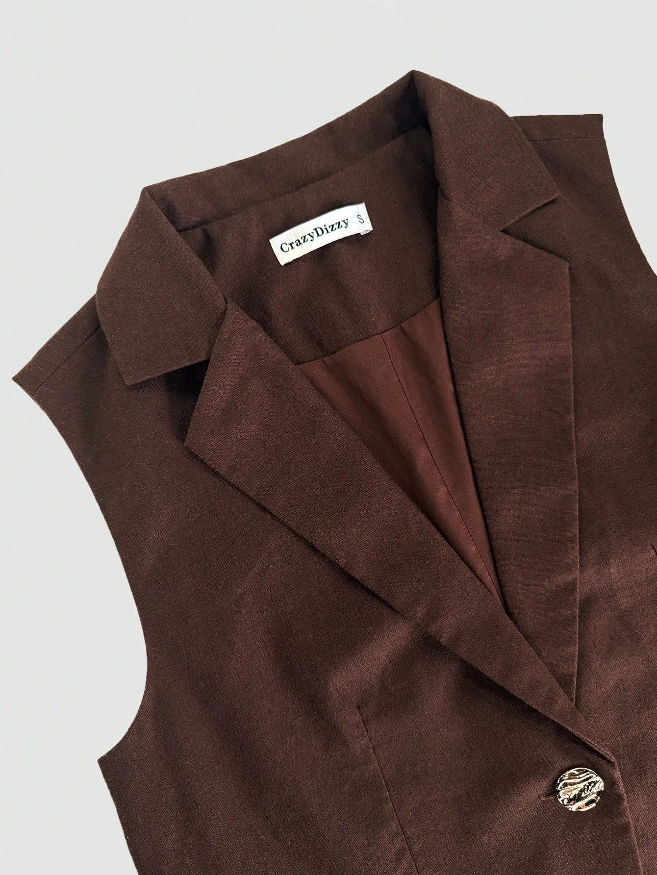 Brown vest with a brand label on a light gray background