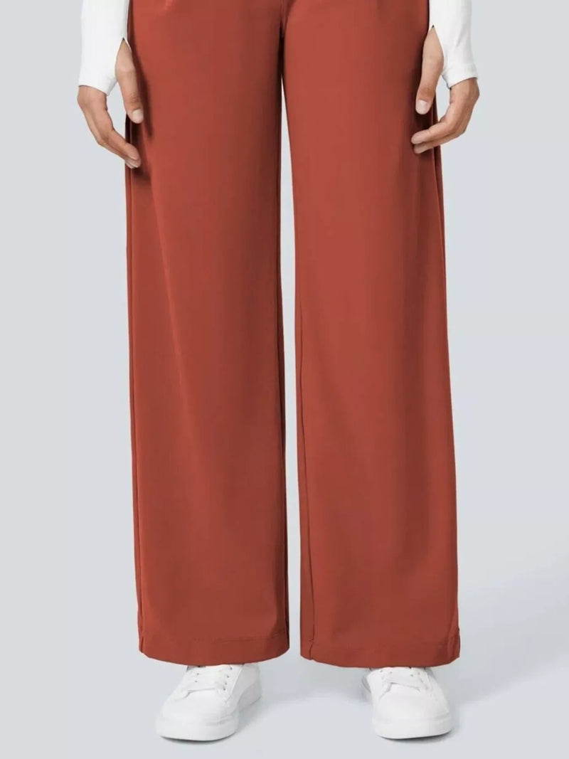 Brown wide-leg pants worn with a white top and white sneakers on a light gray background