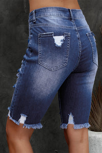 Blue denim shorts with frayed edges on a dark background