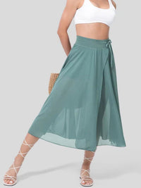 Person wearing a green skirt and white top on a plain background