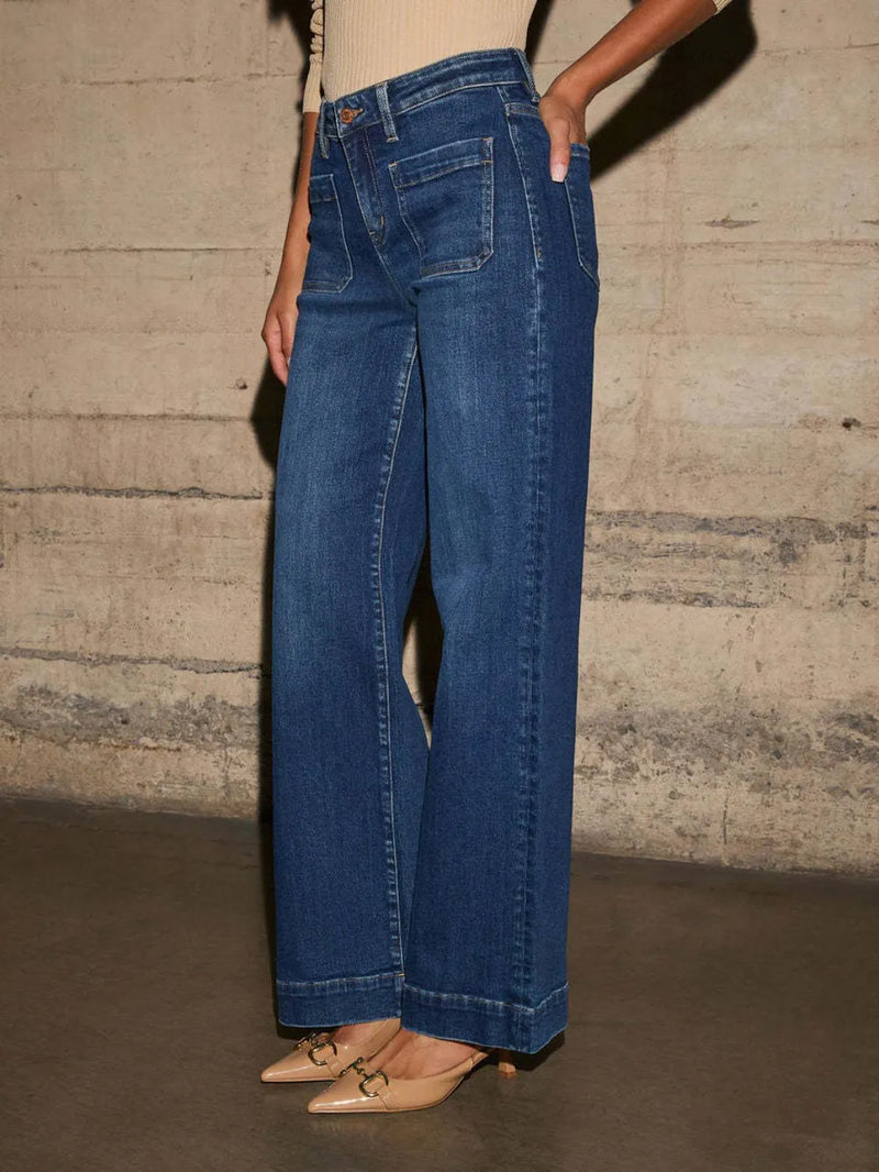Person wearing blue jeans against a textured wall.