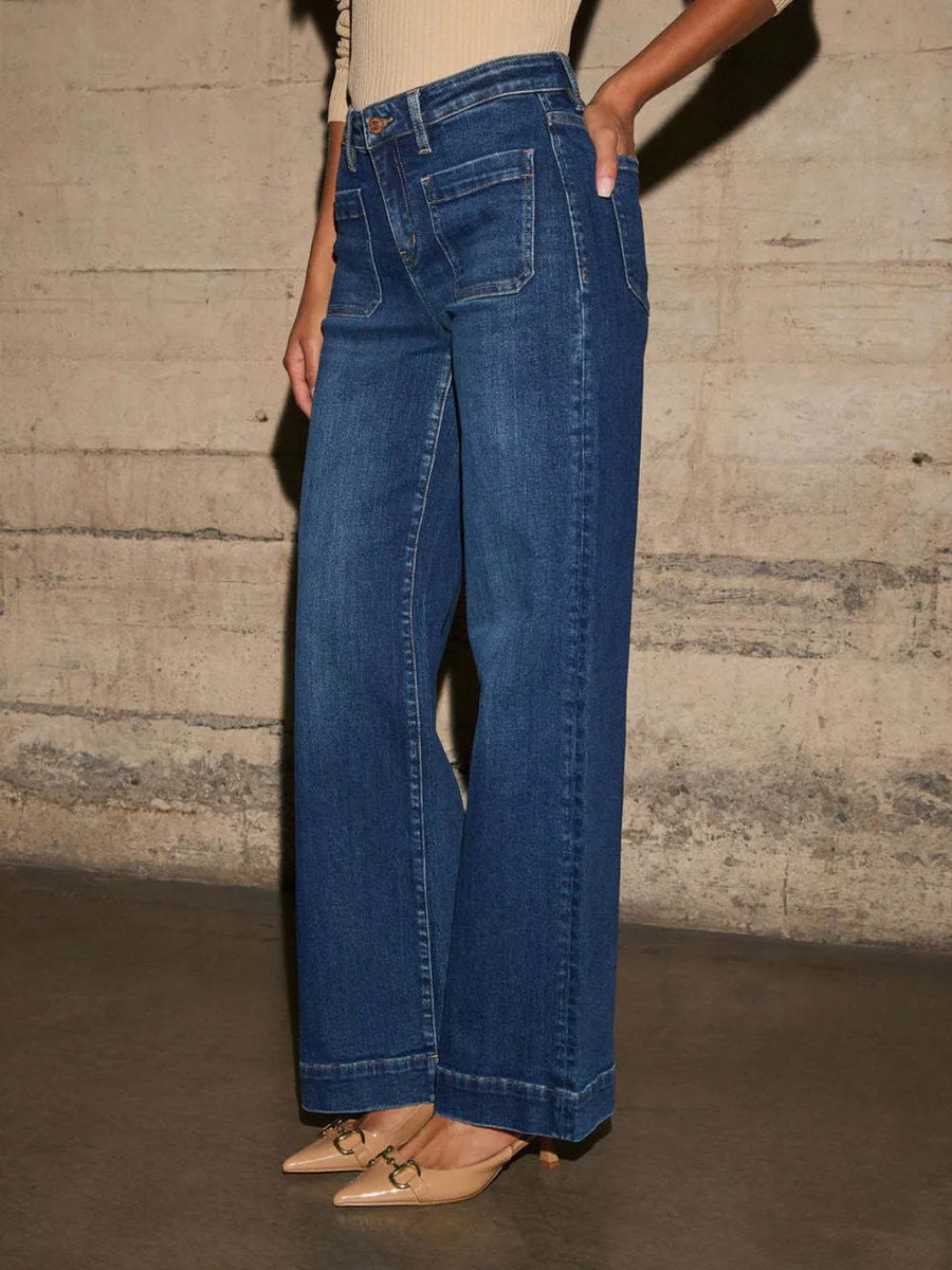 Person wearing blue jeans against a textured wall.